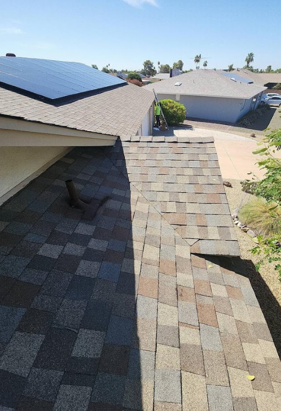 Asphalt shingle roof installation with solar panels, showcasing durable materials and energy efficiency in a residential setting.