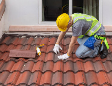 Roofing contractor in safety gear working on clay tile roof, emphasizing quality installation and maintenance for Anthem homes.
