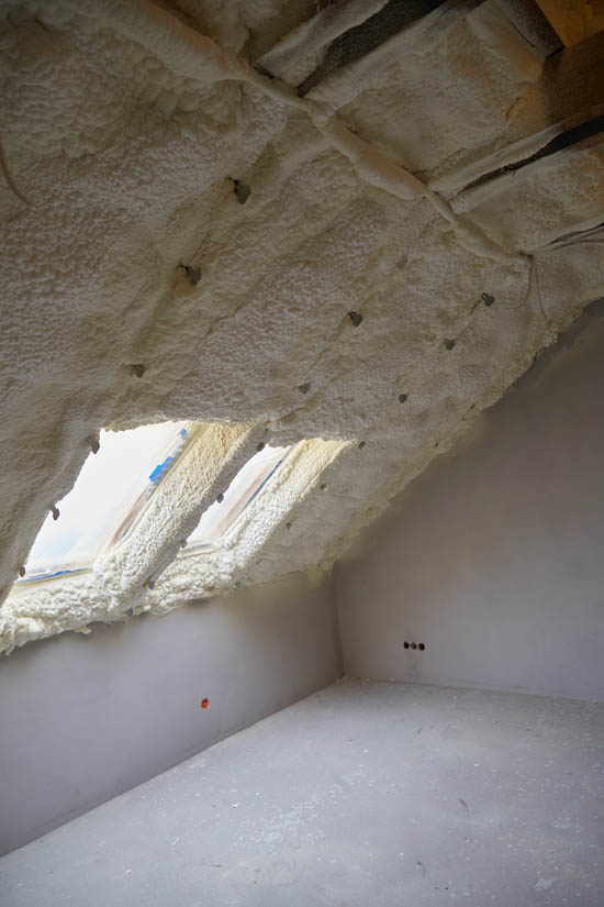 Attic space with freshly applied spray foam insulation on the sloped ceiling, showcasing a clean and professional installation, designed for energy efficiency and temperature control in Arizona homes.