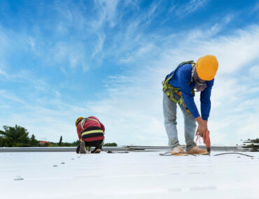 Roofing professionals installing durable roofing system under clear blue sky, emphasizing expert craftsmanship for Chandler homes.