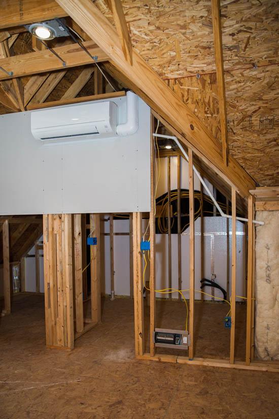 DC mini-split air conditioning unit installed in a partially constructed attic, showcasing clean line sets and electrical connections for energy-efficient cooling solutions.