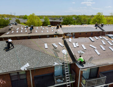 Roofing crew working on asphalt shingle roofs in Glendale, showcasing roof replacement process with solar panel removal and installation.