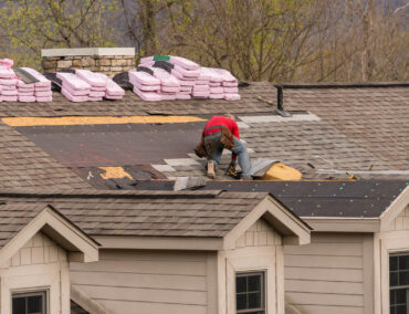 Roofing contractor installing asphalt shingles on a residential home in Glendale, with roofing materials stacked nearby, showcasing Ironclad Roofing's expertise in roof replacements.