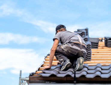 Roofing contractor installing tile on a residential roof in Queen Creek, showcasing craftsmanship and expertise in roof replacements.