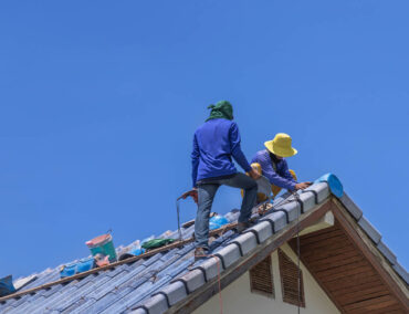 Roofing professionals installing new tile roofing on a residential home under a clear blue sky in Surprise, Arizona, highlighting Ironclad Roofing's craftsmanship and expertise.