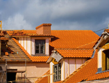 Roofing installation with orange clay tiles on residential buildings, showcasing craftsmanship relevant to Ironclad Roofing's services in Surprise, AZ.