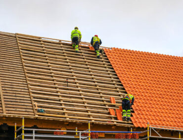 Roofing professionals installing clay tile and wooden framework on a residential roof in Surprise, Arizona, showcasing expert craftsmanship and roofing services.