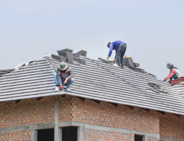 Roofers installing asphalt shingles on a residential home in Tempe, showcasing expert craftsmanship and roofing services.