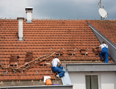 Roofing professionals replacing tiles on a residential roof, showcasing expert craftsmanship for Tucson's climate challenges.